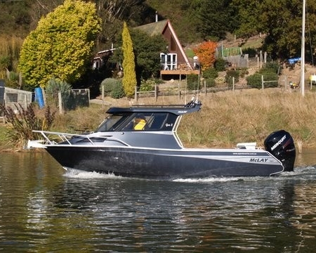 Grey and white boat with white rails and hard top canopy, and black motor on the water