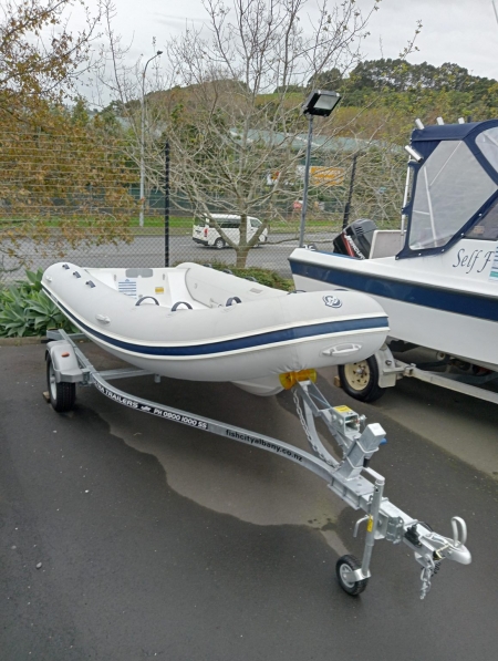 White tube boat with navy stripe and navy handles on a trailer